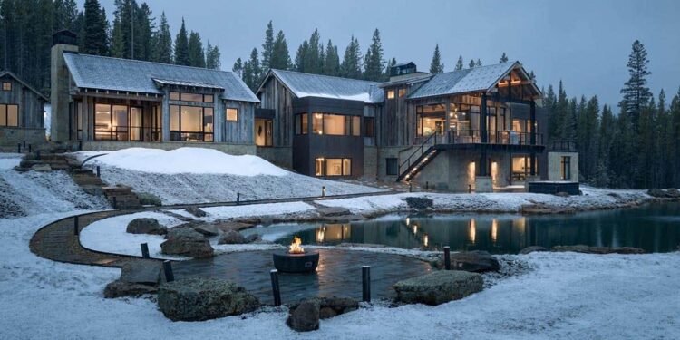 Mountain home with a fire pit terrace beside a pond in the snow