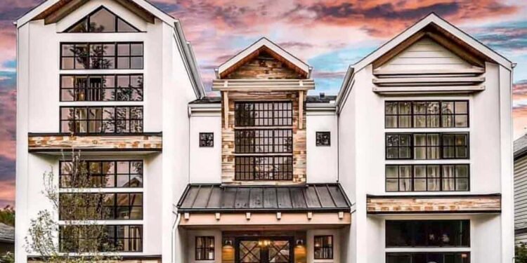 Modern farmhouse exterior in Calgary at sunset, with white gables, black-framed windows, and reclaimed wood accents